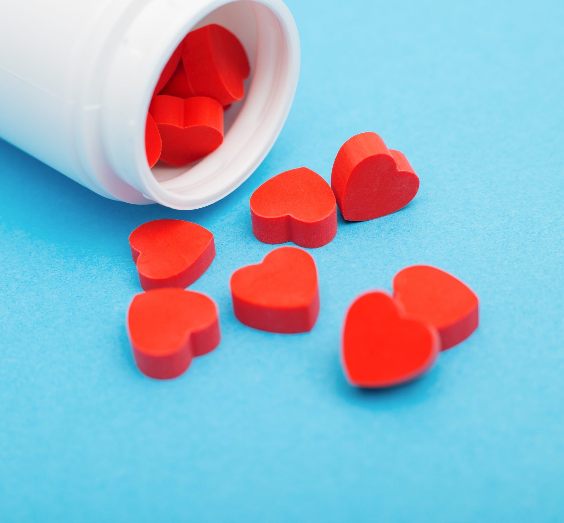 Red,Heart,Shaped,Pills,With,Plastic,Bottle,On,Blue,Background.concept